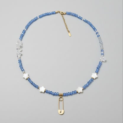 Beaded necklace with blue glass beads, clear quart beads, star shaped shell beads, and gold plated safety pin pendant. 