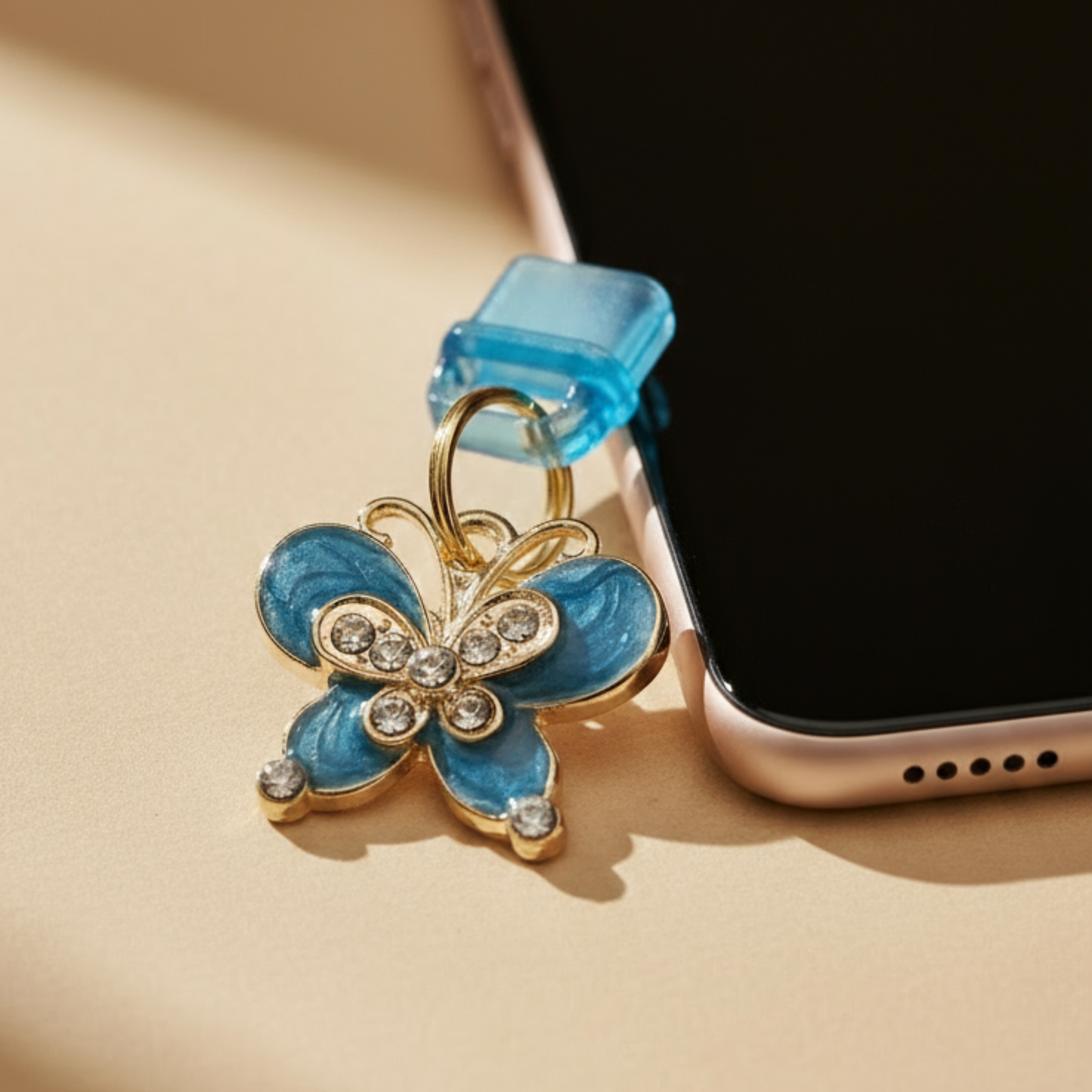 Charging port phone dust cover -Butterfly-shaped charm with blue and gold colors on a beige surface