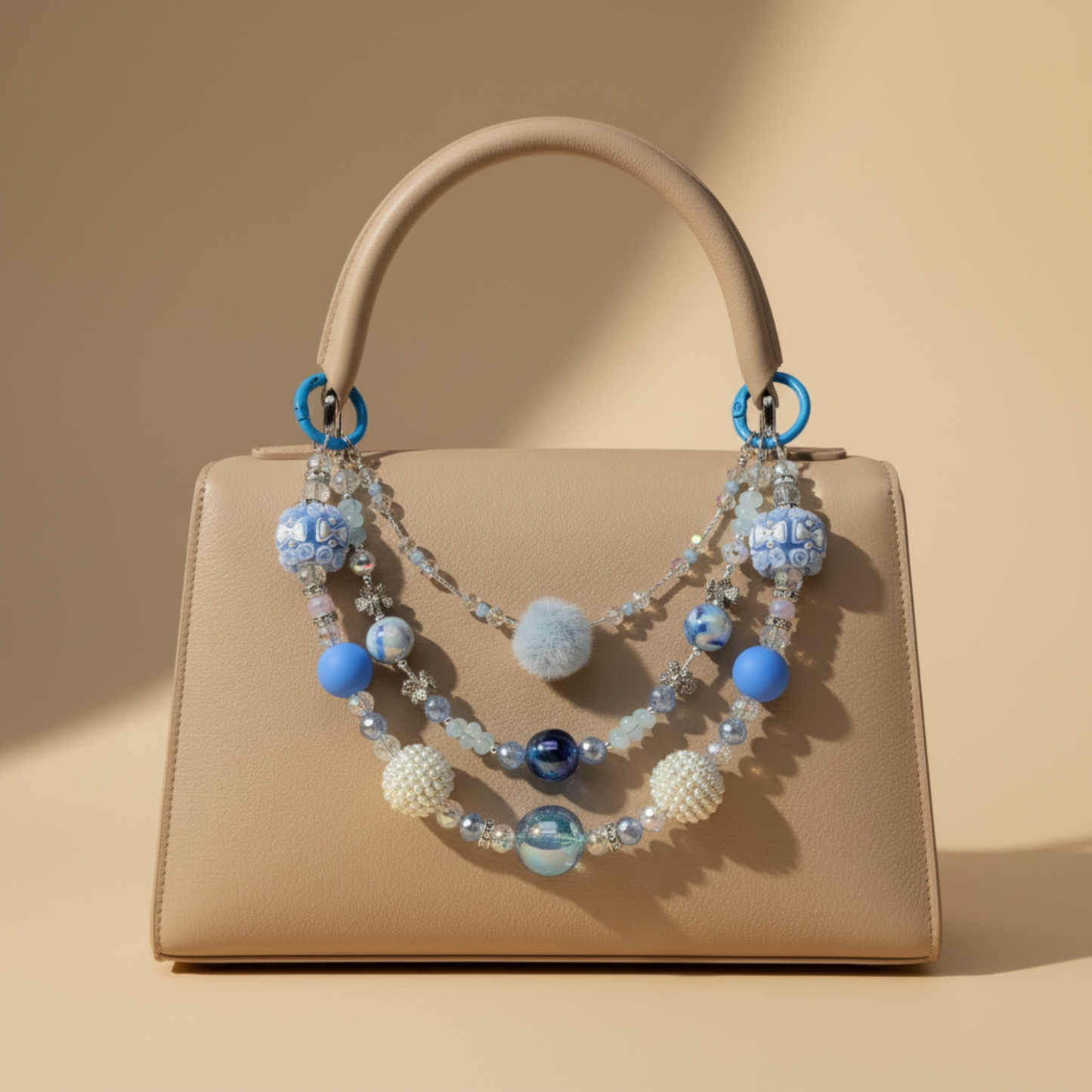 Beige handbag with a decorative purse charm made of blue, white, and metal beads on a beige background