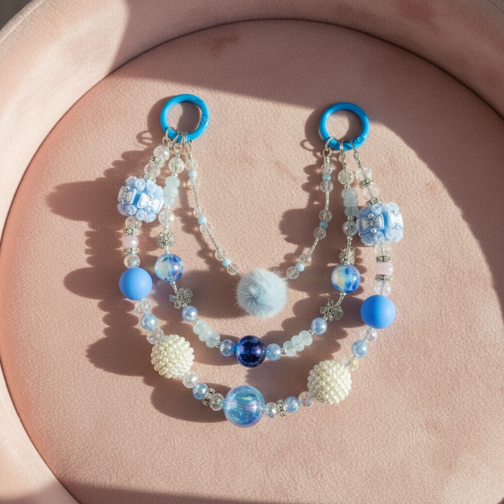 Beaded purse charm with blue and white beads on a pink surface