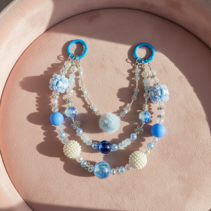 Beaded purse charm with blue and white beads on a pink surface