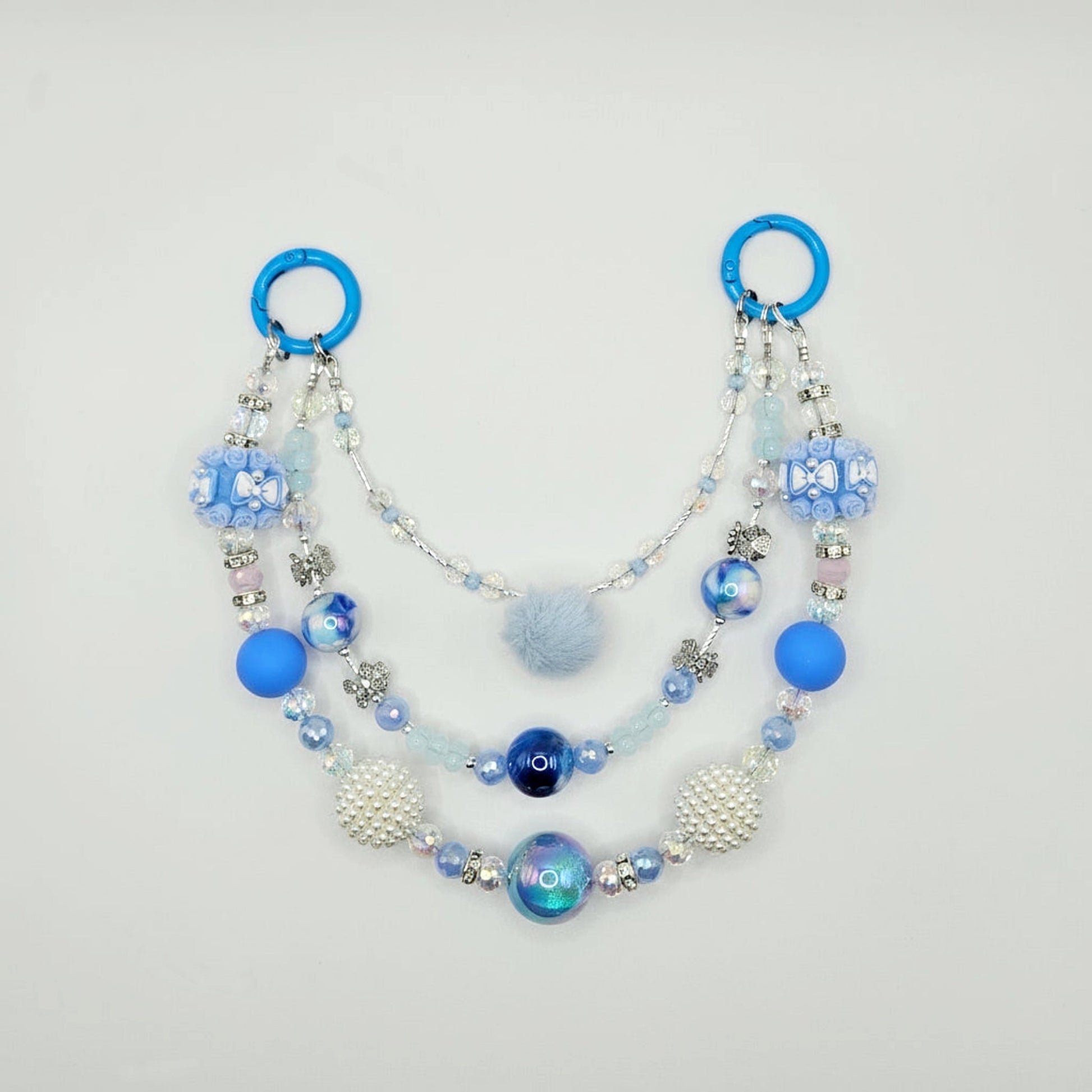 Beaded purse charm with blue and white elements on a light gray background
