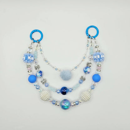Beaded purse charm with blue and white elements on a light gray background