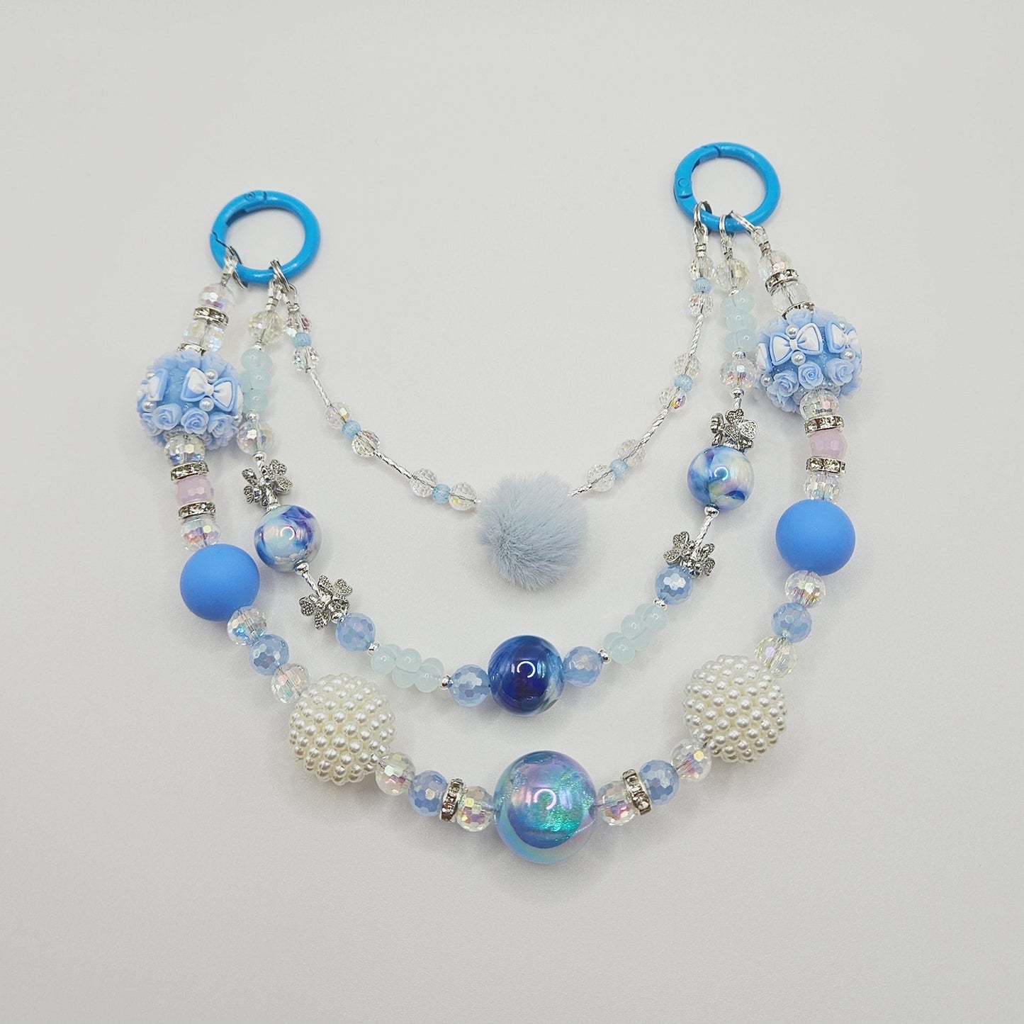 Beaded purse charm with blue and white beads on a light gray background