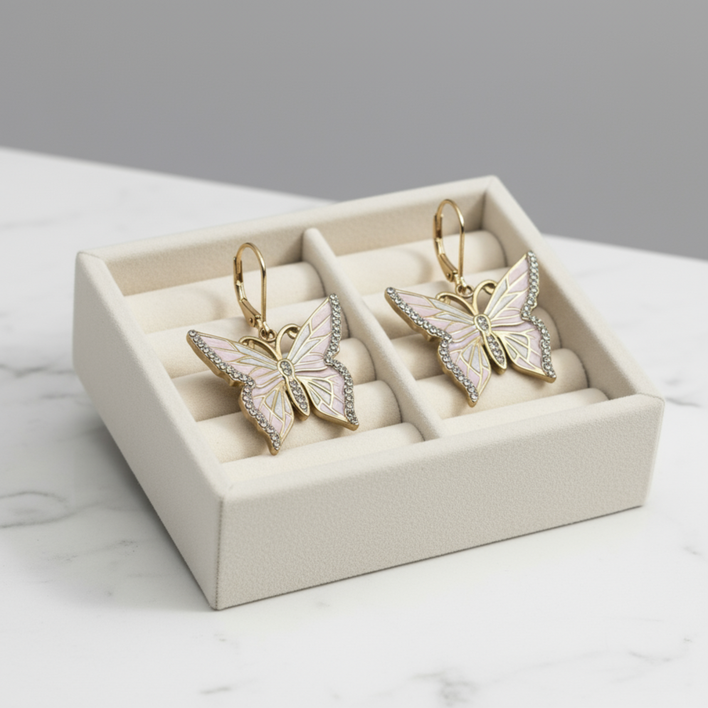 Butterfly-shaped earrings in a jewelry box on a marble surface