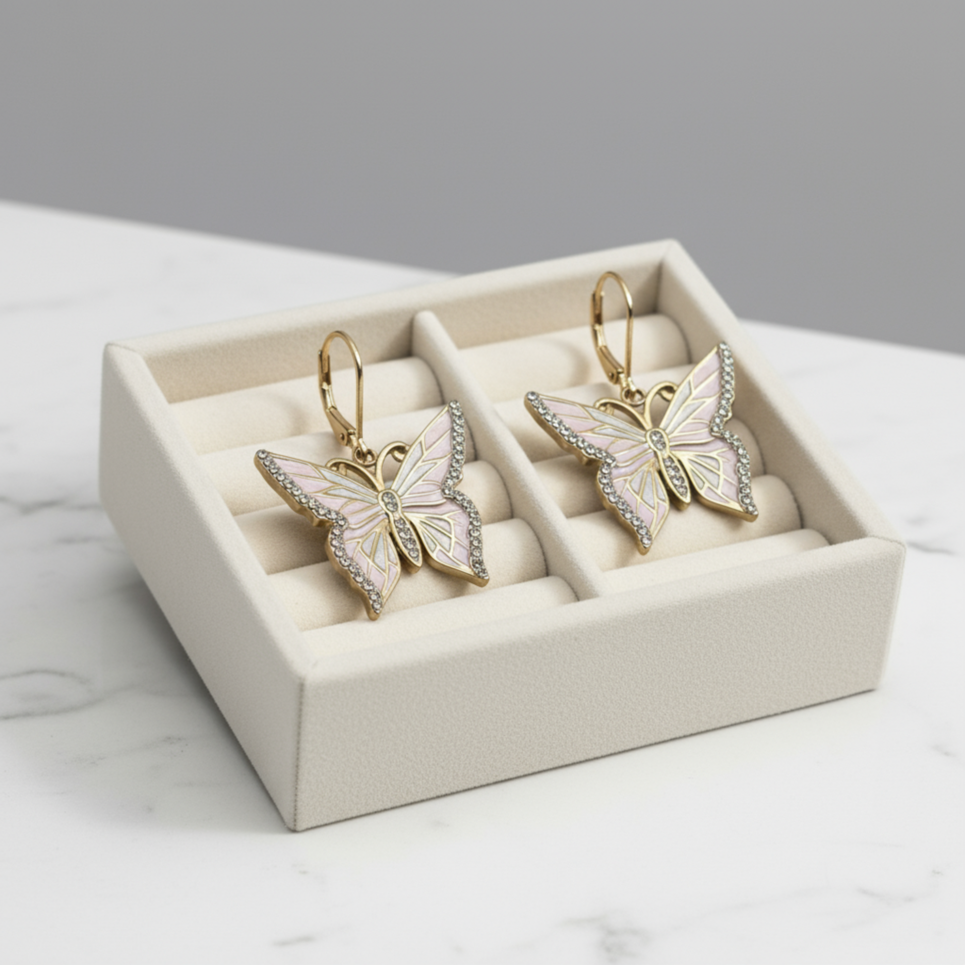 Butterfly-shaped earrings in a jewelry box on a marble surface