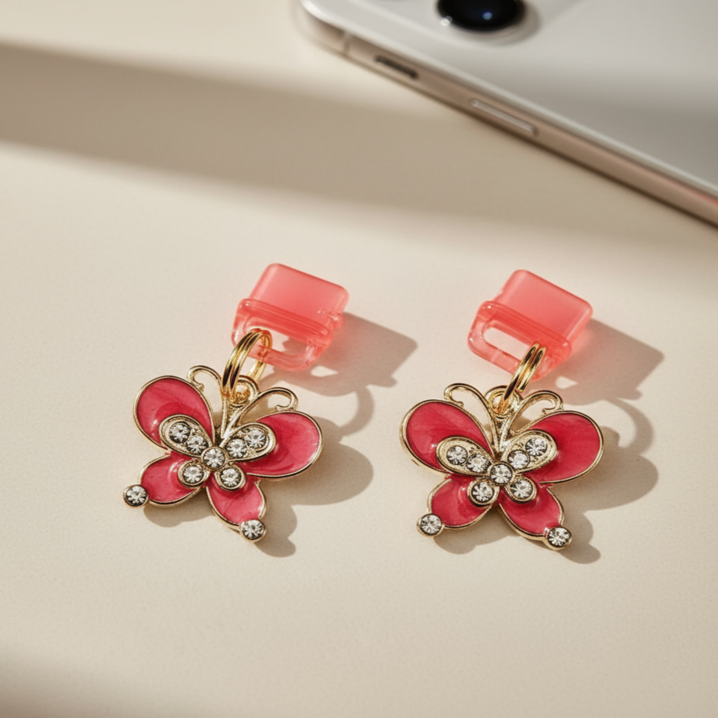 Charging port phone dust cover -Butterfly-shaped charm with pink and gold colors on a beige surface