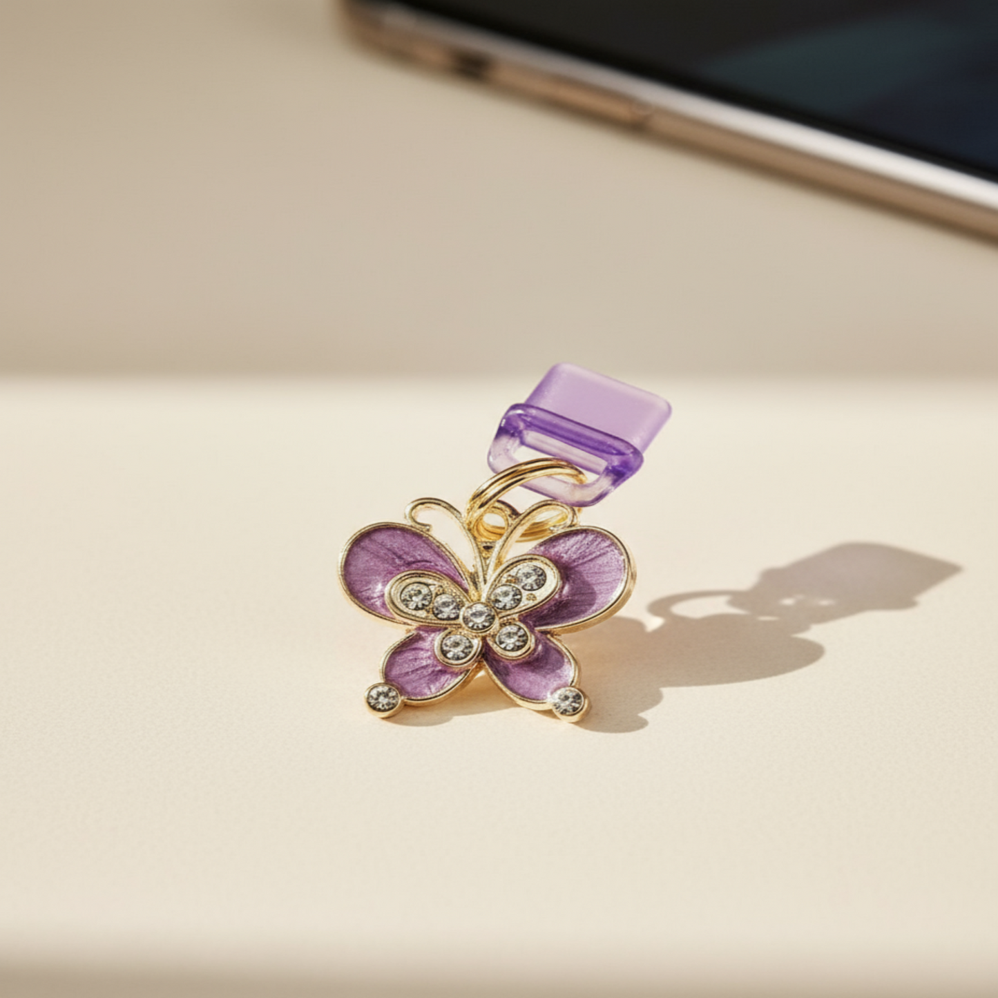 Charging port phone dust cover -Butterfly-shaped charm with purple and gold colors on a beige surface